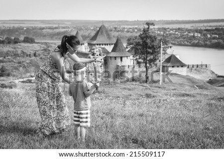 Mom and son on the ancient path. Against the background of a medieval castle. Mom and son look at the medieval fortress. Travel, mom and son, fortress, history.