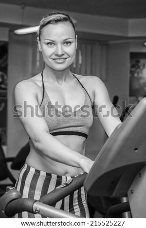 The beautiful blonde in the gym. The coach stands on the track simulator. Girl shows exercise. Treadmill, fitness, running, healthy living, trainnings - The concept of health. Article about the sport.