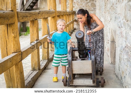 Mother and Child Tourists With Canon. Mom and son in a medieval castle, near the cannon. Travel, fortress, castle, history. Mom and son outdoors.
