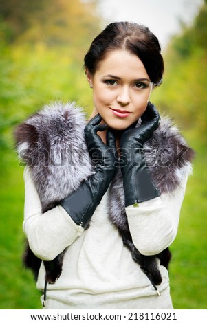 stylish beautiful girl posing outdoors in fur scharf,  and leather gloves