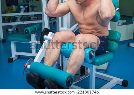 Closeup of a muscular young man lifting weights in the gym.Man makes exercises. Sport, power, dumbbells, tension, exercise - the concept of a healthy lifestyle. Article about fitness and sports.