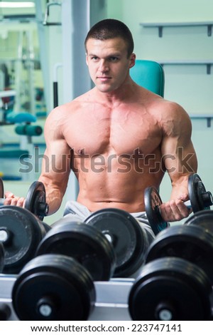 Muscular arm in the gym. Hand holding a dumbbell in suspense. Training, sports, hand, dumbbell, trainnings. - The concept of a healthy lifestyle and fitness. article about fitness and sports.