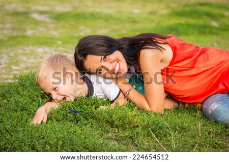 Mom and son outdoors. Mom and son lying on the grass. Mom hugging her son. Holidays, family, nature, children - the concept of a family holiday in the countryside.