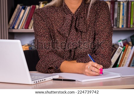 Portrait of a young business woman using laptop at office. Business woman working in the office at the table.young business woman reading sitting at the desk on books background.