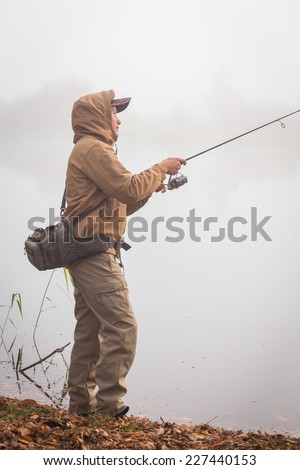 Fisherman on the river bank. Autumn fishing. Fisherman in his hand holding spinning. Fishing, spinning reel, fish, Breg rivers. - The concept of a rural getaway. Article about fishing.