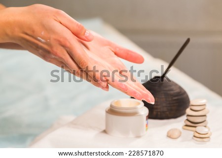 Spa treatment for hands. Application of hand cream in a spa salon. Manicure, hand care. Relaxation, fun, hands, care background. Candles in the background.