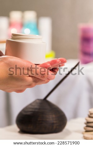 Spa treatment for hands. Application of hand cream in a spa salon. Manicure, hand care. Relaxation, fun, hands, care background. Candles in the background.