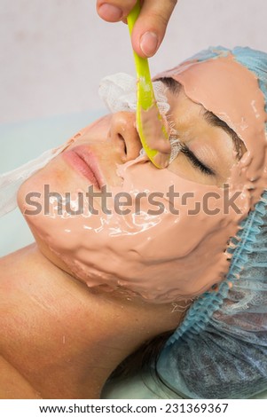 Spa therapy for young woman receiving facial mask at beauty salon.Cosmetic truant, spa, beauty, skin, rubber mask - the concept of skin care. Article about cosmetology.