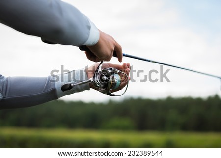 Fishing in river.A fisherman with a fishing rod on the river bank. Man fisherman catches a fish.Fishing, spinning reel, fish, Breg rivers. - The concept of a rural getaway. Article about fishing.