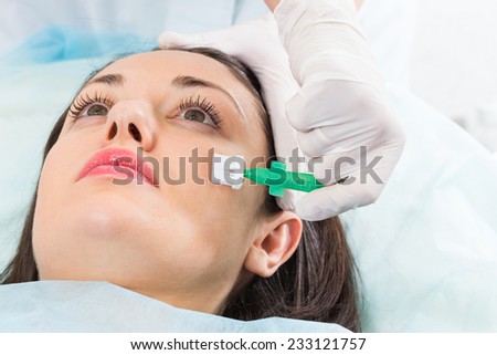 Young girl in a beauty parlor. Beautician spa facial treatment, a young girl. Application of peeling on the face, a special brush. Beauty, skin care, cream application - Concept facials.