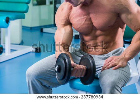Strong and muscular guy with dumbbell. Handsome muscular man working out with dumbbells in gym.Sport, power, dumbbells, tension, exercise - the concept of a healthy lifestyle.