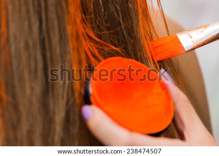 Hair coloring brush, painting hair orange. Makeup artist in the salon hair color model. Creativity, makeup, make-up, hair coloring.
