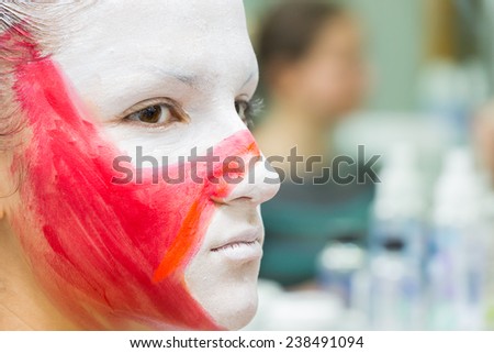 Putting drawing on the model\'s face. Makeup artist draws a star on  face of the model with a brush. Red star on face, creativity, make-up, the idea, brush, creative process.