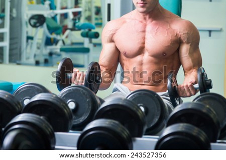 The strong man at the gym doing exercises with heavy weights. Training with heavy weights. Strength training in the gym. Strong arms, strength training. Muscle definition.