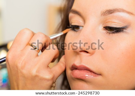 Work of make-up artist. Makeup artist apply makeup on the face of the girl model. Painting of eyebrows. Application of shadows on the model's eyes.