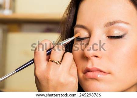 Work of make-up artist. Makeup artist apply makeup on the face of the girl model. Painting of eyebrows. Application of shadows on the model's eyes.