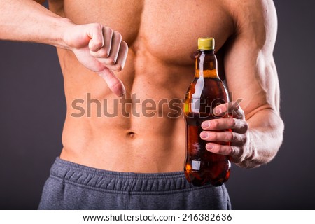 The idea of a healthy diet. Bodybuilder pours beer. Beer - not a healthy diet. Muscular guy with a beer in hand.