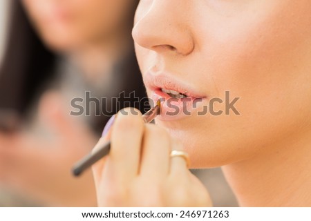 Make up process. The making of nude look for lips. Fresh and sparkling lips made by a lip gloss and professional lip brush. The finishing accent for every make up.
