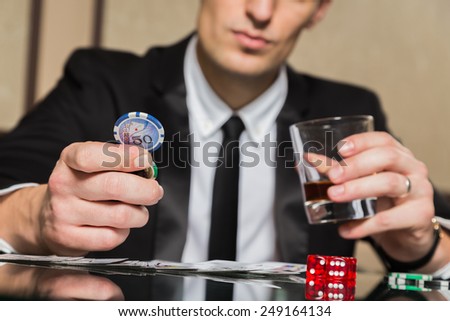 A young man in a business suit sitting at the poker table. Man gambles. The player at the gaming table playing cards.
