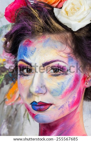 The creative, bright, color makeup. Floral makeup. Art makeup. Tone, powder, make-up. Multi-colored roses in her hair girl. Creative floral makeup on the model, background floral pattern.