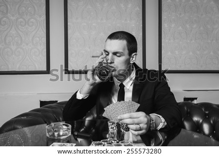 Poker player. Young guy in the casino at the gaming table. Man gambling, card games. Cards, chips, whiskey, cigarettes, poker, card game, gambling - gambling concept.