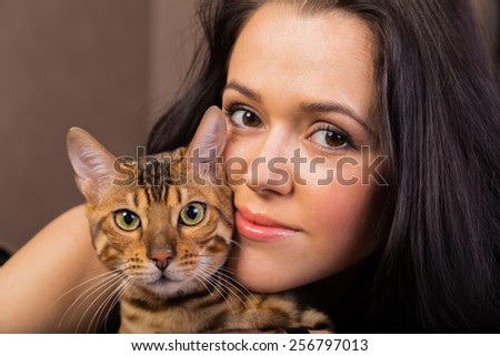 Beautiful woman with cat portrait. Brunette with bengal cat close-up.
