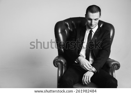 Male businessman sitting on a green leather chair on a white background. The man exudes self-confidence, success, wealth. Money, success, prosperity.