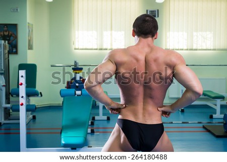 Man at the gym. Man makes exercises. Sport, power, dumbbells, tension, exercise - the concept of a healthy lifestyle. Article about fitness and sports.