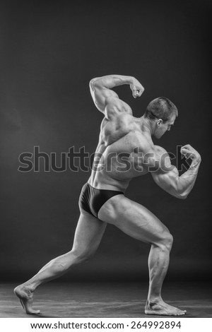 Classic bodybuilder, posing on a black background. Athletic man showing his muscle in suspense. Sports, strength, bodybuilding, physical strength.