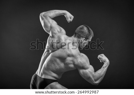Classic bodybuilder, posing on a black background. Athletic man showing his muscle in suspense. Sports, strength, bodybuilding, physical strength.