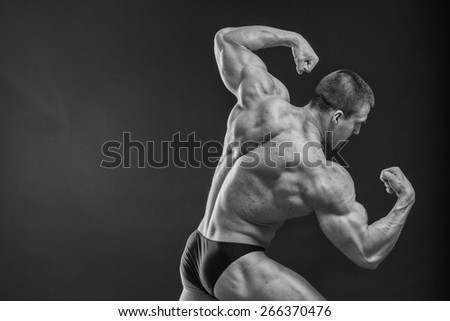 Muscular man bodybuilder. Man posing on a black background, shows his muscles. Bodybuilding, posing, black background, muscles - the concept of bodybuilding. Article about bodybuilding.