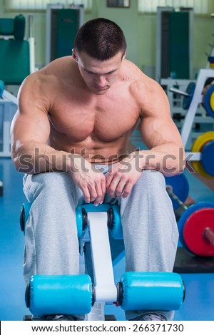 A man pumping abdominal muscles. Man in the gym. Man makes exercises. Sport, power, dumbbells, tension, exercise - the concept of a healthy lifestyle. Article about fitness and sports.