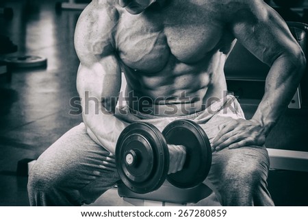 The process of physical exercise with dumbbells. The man is engaged in the gym. Training in the gym. Healthy lifestyle. Photo in creative.