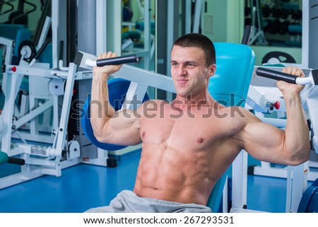 Man in the gym. Working out with weights.Man makes exercises. Sport, power, dumbbells, tension, exercise - the concept of a healthy lifestyle. Article about fitness and sports.