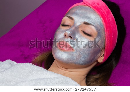 Application of rejuvenating mask on the face of the girl. Cosmetic procedures for the face. Hands beautician applied mask on face of the girl. Facial treatment in a beauty salon.