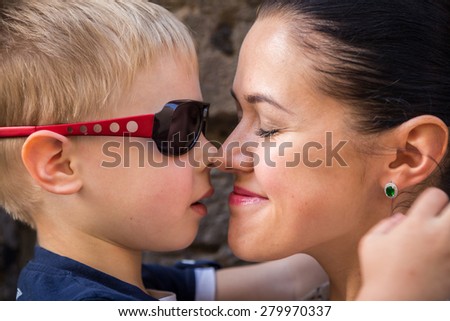 Mom and son. Baby and mom near a stone wall, hugging, kissing, show love. Family values, the concept of family relations.