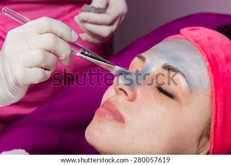 The cosmetic procedures for the face. Makeup artist applies invigorating mask on the face of the model. Beauty treatments in the spa salon. Facial Skin Care.
