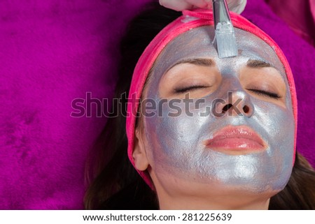 Facial Skin Care. Drawing a silver mask on the face of a beautiful girl. Anti-aging facial mask.