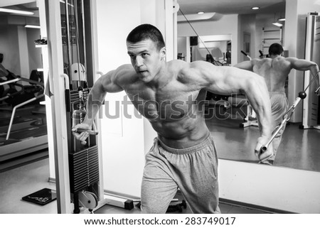 Muscular man working out with weights in gym. Man makes exercises.