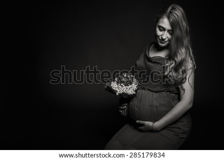 Subject pregnancy, waiting child. The ninth month of pregnancy. Pregnant girl with flowers. Photography in low key, sepia. Pregnant woman.