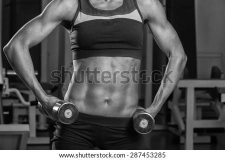 Gym woman push-up strength pushup exercise with dumbbell in a fitness workout. Athletic young woman doing exercises.