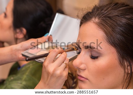 Makeup artist apply makeup to a model.
