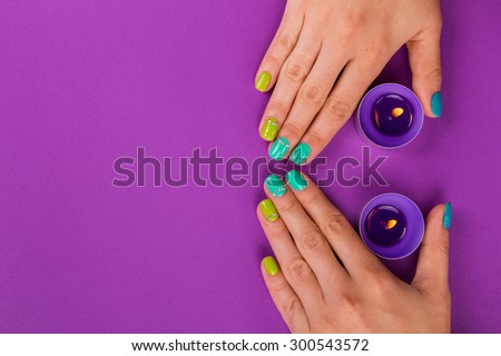 Beautiful manicure on purple background. Girl holding a candle. Nail care. The concept of nail services.