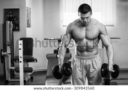 Muscular guy working with free weights. Work on the arm muscles. Professional bodybuilding. Work on yourself in the gym.