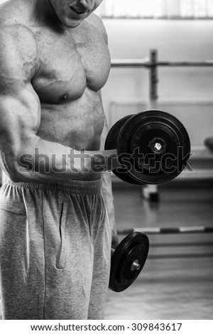 Muscular guy working with free weights. Work on the arm muscles. Professional bodybuilding. Work on yourself in the gym.