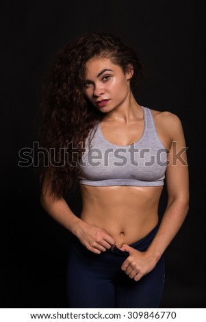 Sport brunette posing on black background. Women\'s fitness. Posing with sports equipment. Portrait photo.
