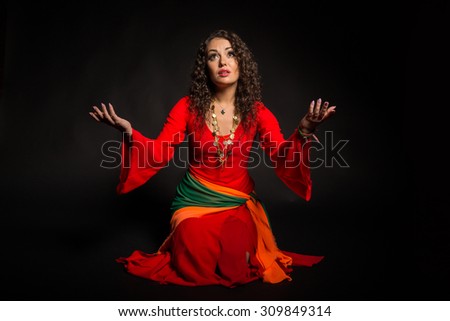 Brunette with gypsy dress. Traditional Gypsy women\'s accessories and dresses. Emotions and gypsy flavor. Gypsy on a black background.