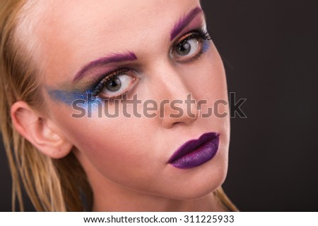 Professional makeup. Art makeup. Bright and unusual make-up on beautiful model. Beautiful blonde on a dark background. Portrait photo.