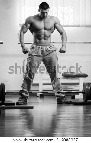Athlete demonstrates muscles in the gym. Muscle tension of exercise performed. Weight training. Bench weights and work with dumbbells.