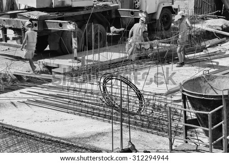 Compilation of metal structures for pouring concrete. Preparations for the inundation of supporting walls. The metal frame and the reinforcing mesh. Working fasten metal plate on a construction site.